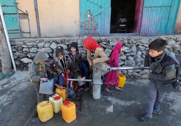 Niños afganos cogen agua de una fuente en Kabul 