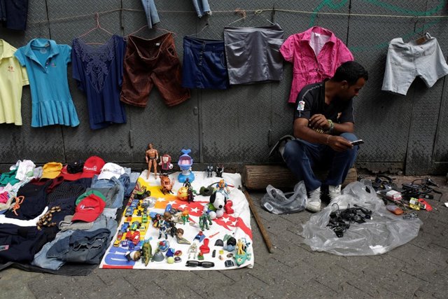 A vendor sits next to second-hand toys and clothes at a street market in the slu