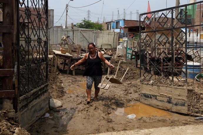 A woman carries a chair after a landslide and flood in Lurigancho district in Ch