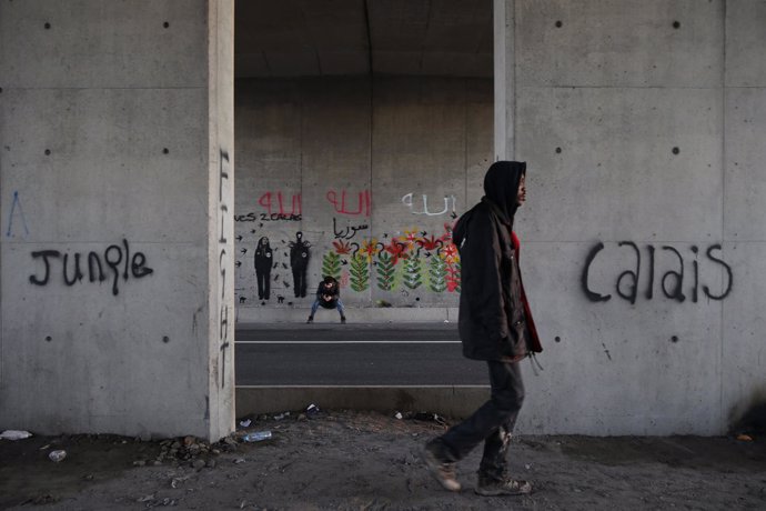 Inmigrante caminando en una zona de campamento improvisado en Calais