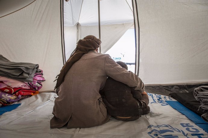 Un padre con su hijo en un campo de desplazados en Siria