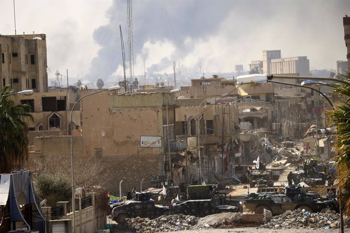 Una calle de Mosul y columnas de humo al fondo