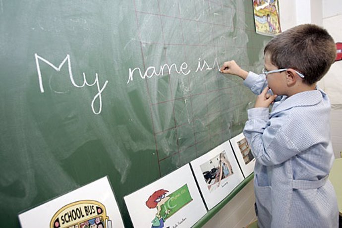 Imagen de archivo de un niño que escribe inglés en la pizarra del colegio