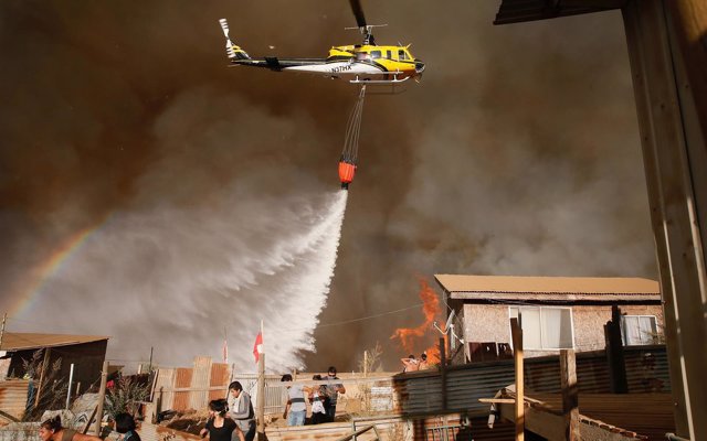 A helicopter makes a water drop to prevent a wildfire from spreading to homes in