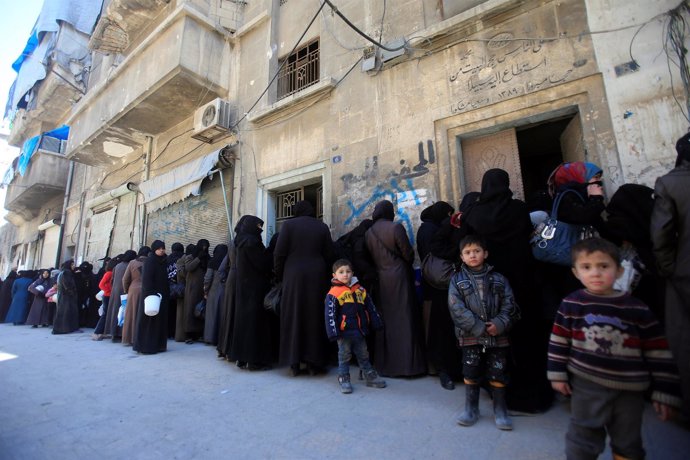 Mujeres y niños sirios hacen cola para recibir ayuda en Alepo.