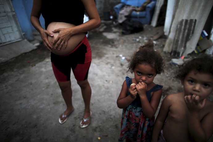 Patricia Araujo (L), 23, who is seven-months pregnant, stands next to children a