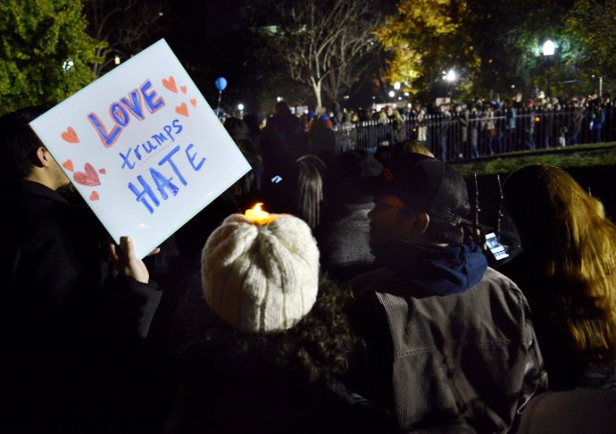 Un manifestante con una pancarta que dice "el amor triunfa sobre el odio"