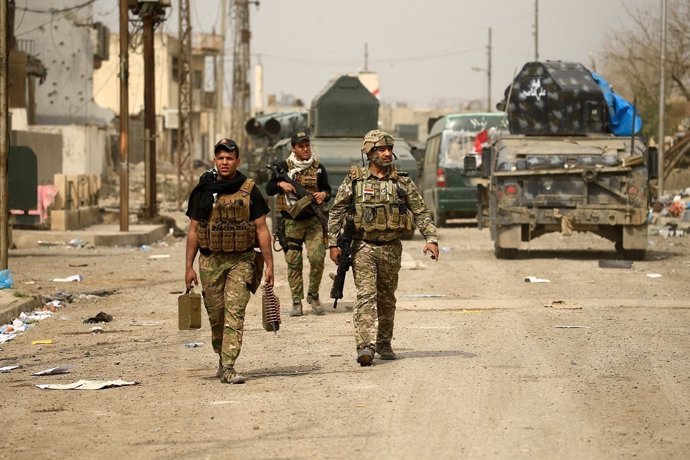 Iraqi rapid response members carry their weapons during a battle against Islamic