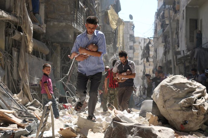 Hombre sirios llevan en brazos a bebés en Alepo