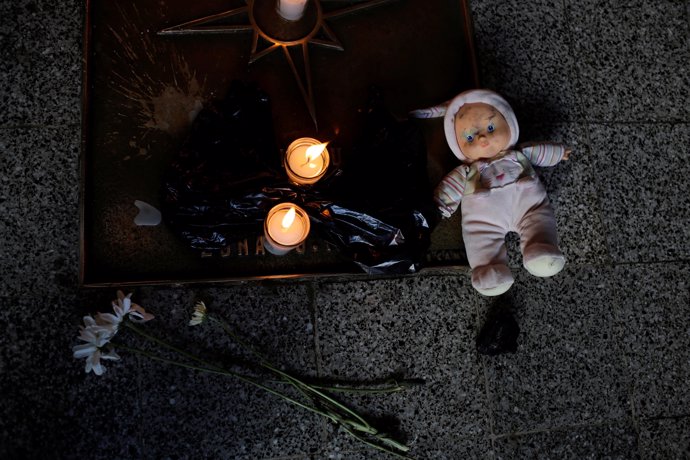 A doll and candles are placed during a protest to demand justice for the victims