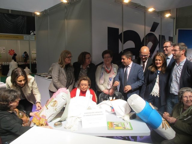 Autoridades observan a un grupo de mujeres que realizan encaje de bolillos.