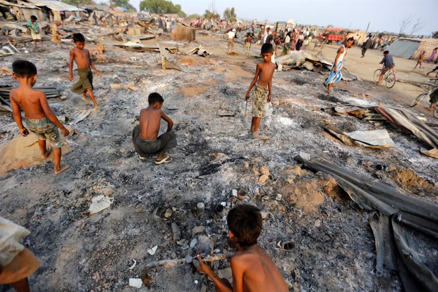 Niños buscando entre sus viviendas quemadas en Rajine, Birmania