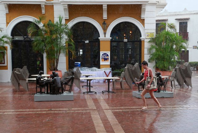 A woman walks under the rain at San Pedro Square in Cartagena, Colombia, Septemb