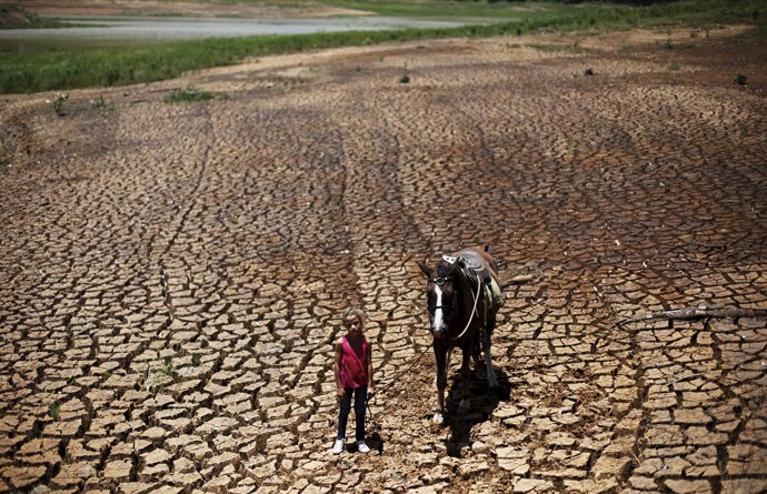 Paula, 7, poses with her horse on the cracked ground of Atibainha dam, part of t