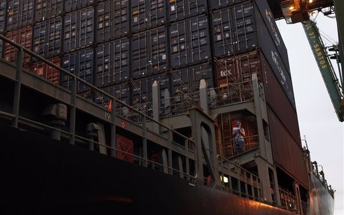 Un trabajador portuario junto a una serie de contenedores 