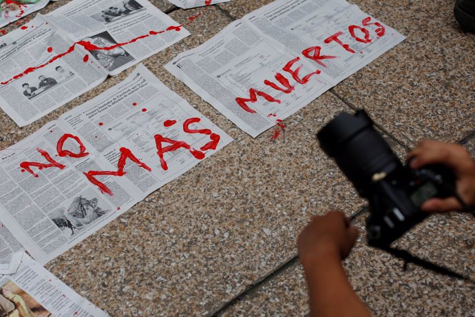 Journalists and activist paint on news papers with fake blood during a protest a