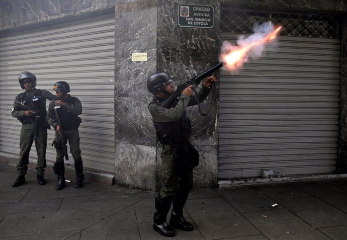 Un policía venezolano dispara gas lacrimógeno durante la marcha de la oposición.