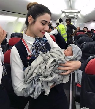 Un miembro de la tripulación de un avión sujeta a una niña que nació en el vuelo