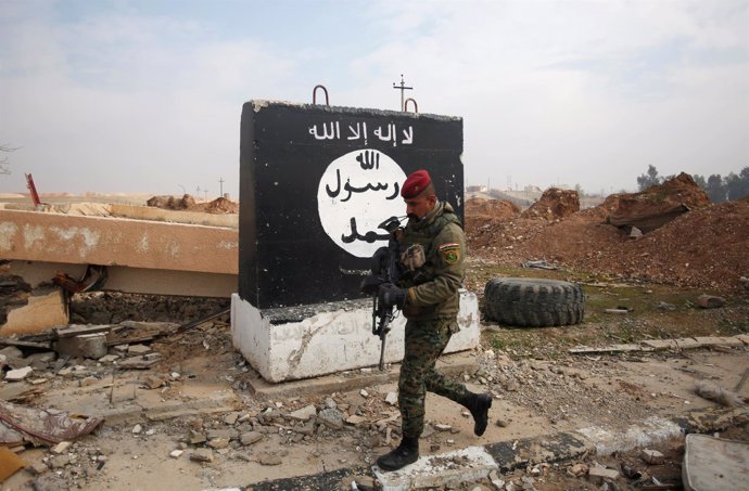Un soldado iraquí pasa al lado de una bandera del Estado Islámico en Mosul 