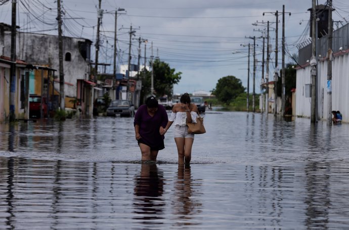 People walk on a flooded street after heavy rainfall in Duran, Ecuador April 4, 