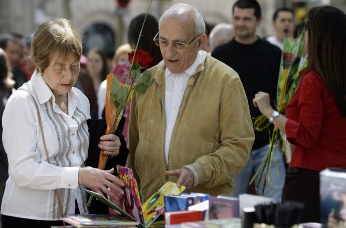 Una pareja mira un libro con un rosa en la mano en Sant Jordi