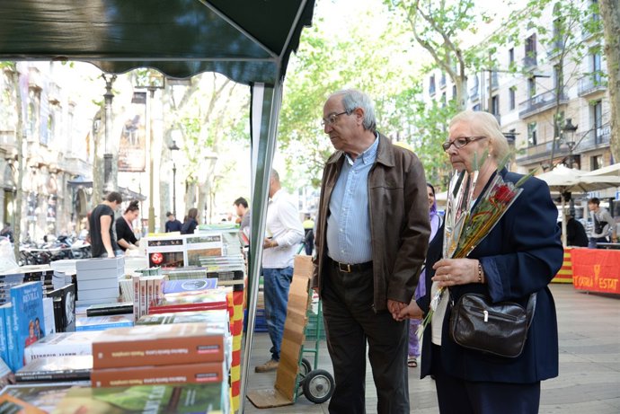 Parella amb una rosa a un stand de llibres per Sant Jordi