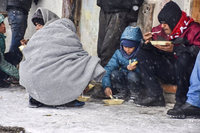 Varios niños comen en un centro de refugiados de Serbia.