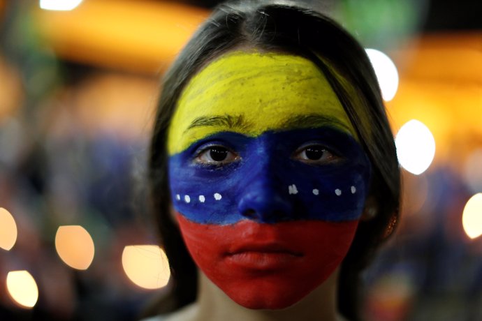 An opposition supporter with her face painted with the colors of the Venezuelan 