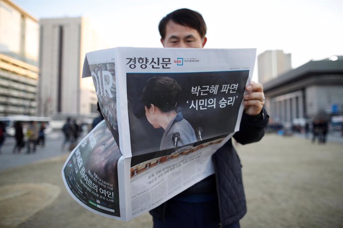 Un surcoreano lee un periódico que muestra el impeachment de Park