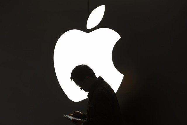 Hombre usando iPad frente al logotipo de Apple
