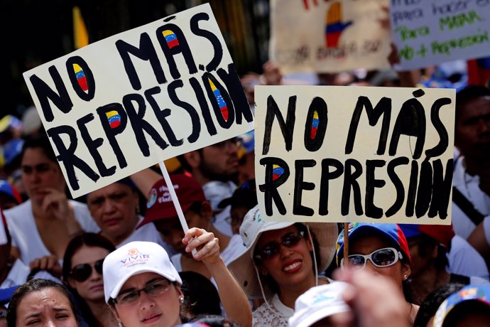 Demonstrators hold placards that read "No more repression" during a women's marc
