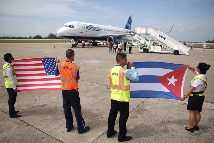Ground crew hold U.S. And Cuban flags near a recently landed JetBlue aeroplane, 