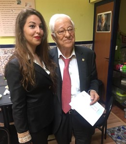 El padre Ángel recibe el cheque de manos de Marta García Saravia.