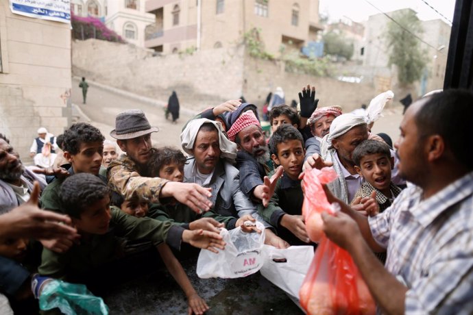 Civiles yemeníes se reúnen para recoger alimentos en Saná, Yemen. 