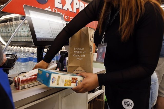 An employee bags groceries for a customer at the express checkout on the opening