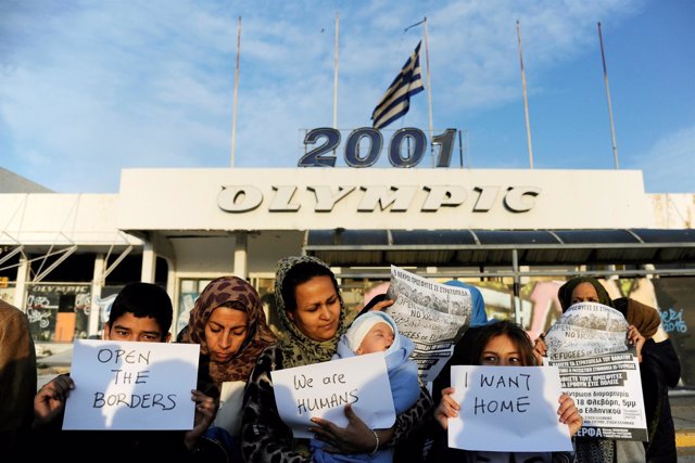 Refugiados con pancartas delante del antiguo aeropuerto de Elliniko, en Atenas