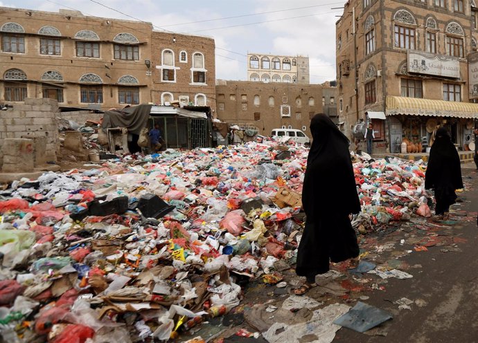Una mujer pasea junto a basura en Saná
