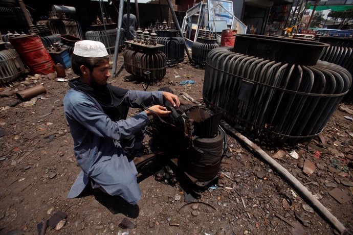 Un hombre arregla un transformador eléctirco en Peshawar, Pakistán