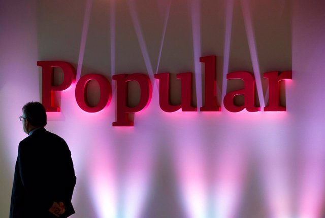 FILE PHOTO: A man stands next to the logo of Spain's Banco Popular during the ba