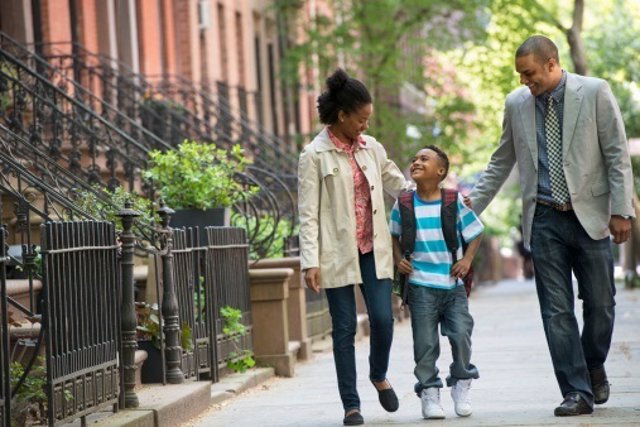 A family outdoors in the city. Two parents and a young boy walking together.