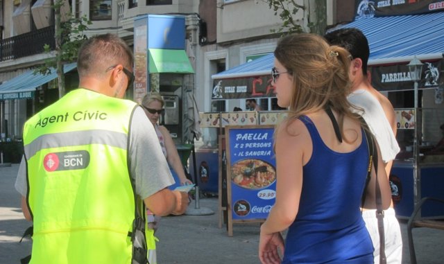Agente cívico con dos turistas en bañador en la Barceloneta