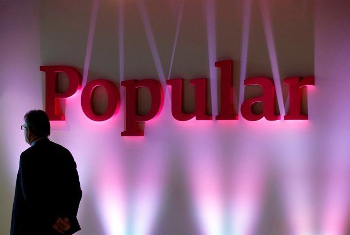 FILE PHOTO: A man stands next to the logo of Spain's Banc Popular during the ba