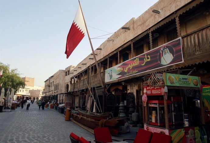 Una tienda con la foto del emir de Qatar y una bandera en Doha