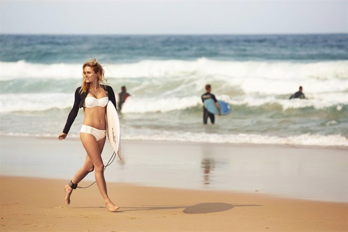 SURFERA EN LA PLAYA CON SU TABLA DE SURF