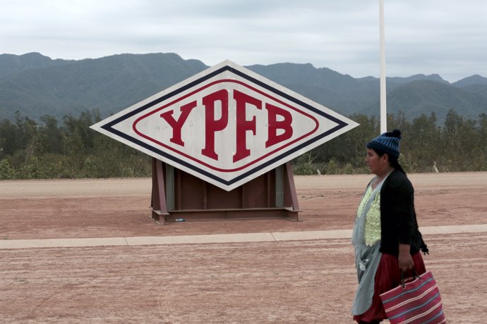 A woman walks in front of the logo of YPFB Corporation at the gas plant in Yacui