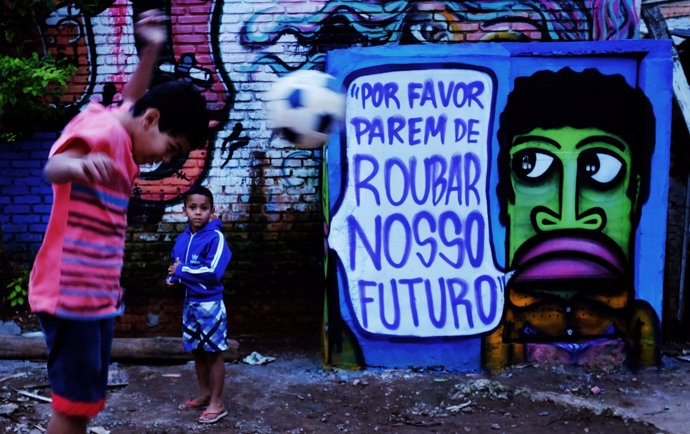 Children play with a ball in front of an artwork by Brazilian artist and activis