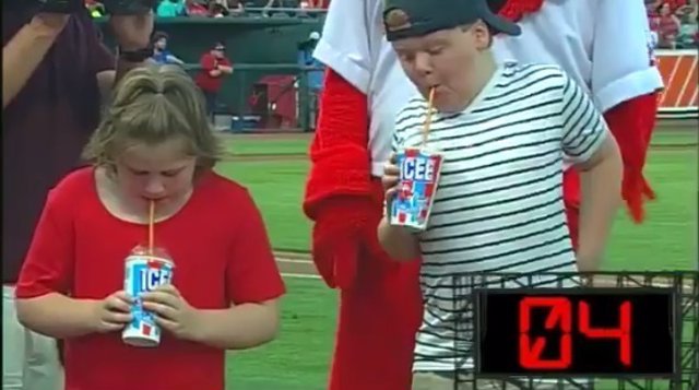 Dos niños compitem por tomarse un granizado más rápido en partido de béisbol