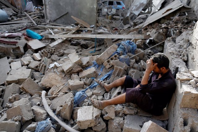 Un hombre sentado sobre los escombros de una casa en Saná