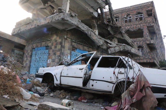 Dos niños juegan en un coche destruido en Taiz