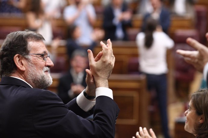 Rajoy aplaude con Pablo Iglesias de fondo tras la votación de la moción